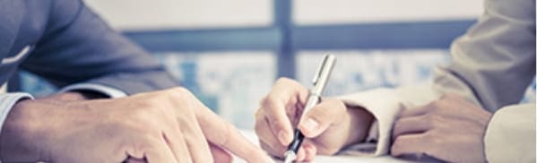 スーツを着た男性二人が相談しながら書類に記入している手元の画像